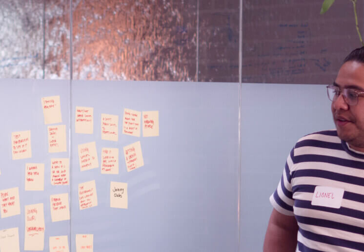 student-in-conference-room-looking-at-sticky-notes-on-a-wall-while-discussing-the-nod-apps-research-and-design-process